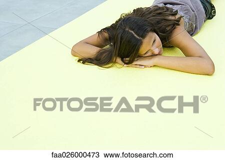 Teenage girl lying on stomach on the ground, head resting on arms View Large Photo Image Stock Image - Teenage girl lying on stomach on the ground, head resting on arms. Fotosearch