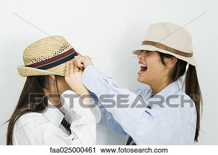 Teenage girl pulling hat over her friend's face, laughing View Large Photo Image Stock Image - Teenage girl pulling hat over her friend's face, laughing. Fotosearch