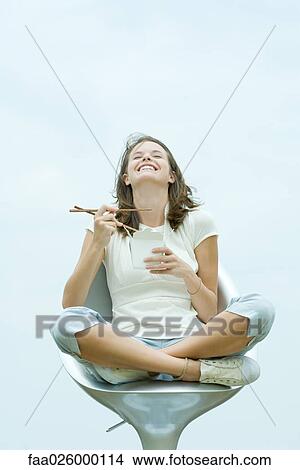 Teenage girl sitting in chair, holding chopsticks and take out food container, eyes closed View Large Photo Image Picture - Teenage girl sitting in chair, holding chopsticks and take out food container, eyes closed. Fotosearch