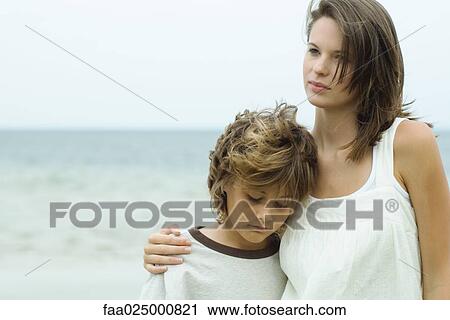 Teenage girl standing on beach looking away, younger brother leaning his head on her shoulder View Large Photo Image Stock Image - Teenage girl standing on beach looking away, younger brother leaning his head on her shoulder. Fotosearch