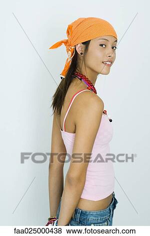 Teenage girl standing with hands behind back, looking over shoulder at camera View Large Photo Image Stock Photo - Teenage girl standing with hands behind back, looking over shoulder at camera. Fotosearch