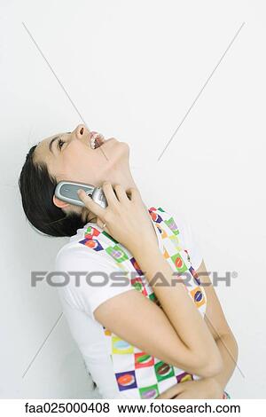 Stock Photo - Teenage girl using cell phone, head back, laughing. Fotosearch