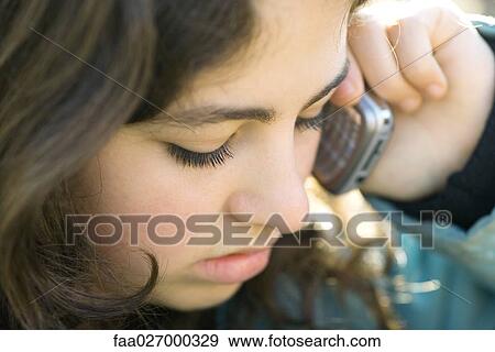 Teenage girl using cell phone, looking down, close-up View Large Photo Image Stock Photo - Teenage girl using cell phone, looking down, close-up. Fotosearch