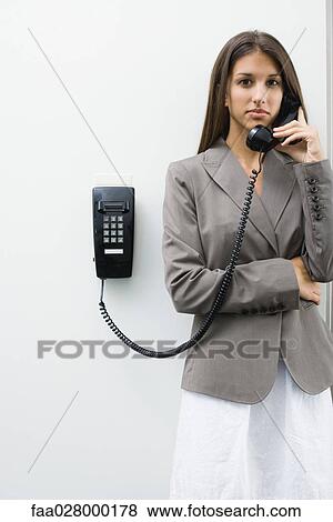 Teenage girl using wall-mounted landline phone, looking at camera View Large Photo Image Stock Photo - Teenage girl using wall-mounted landline phone, looking at camera. Fotosearch