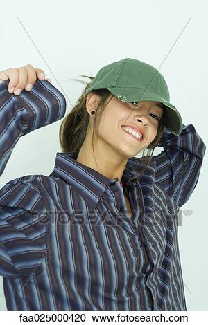Teenage girl wearing button down shirt and cap, smiling at camera with arms raised View Large Photo Image Stock Image - Teenage girl wearing button down shirt and cap, smiling at camera with arms raised. Fotosearch