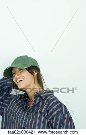 Stock Photo - Teenage girl wearing button down shirt and cap, smiling at camera. Fotosearch