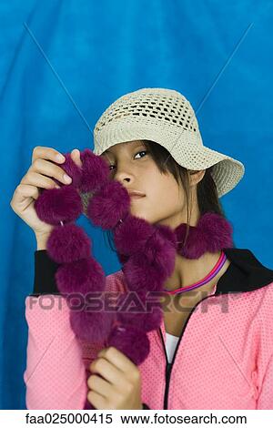 Teenage girl wearing hat, holding boa against face, portrait View Large Photo Image Stock Photography - Teenage girl wearing hat, holding boa against face, portrait. Fotosearch