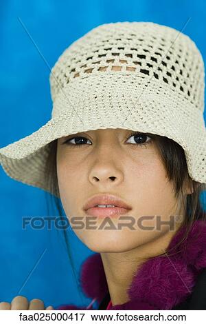 Stock Photo - Teenage girl wearing hat, looking at camera, portrait. Fotosearch