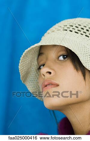 Stock Photograph - Teenage girl wearing hat, looking at camera, close-up. Fotosearch