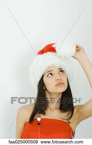 Teenage girl wearing Santa hat, looking up at pom-pom View Large Photo Image Stock Photo - Teenage girl wearing Santa hat, looking up at pom-pom. Fotosearch