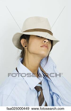 Stock Photo - Teenage girl wearing tie, looking out from under hat at camera. Fotosearch