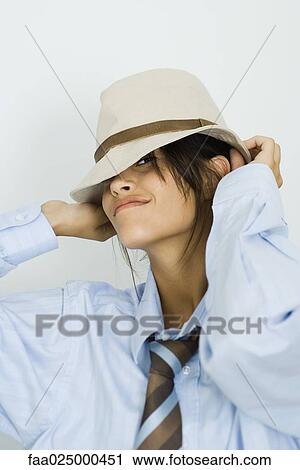 Teenage girl wearing tie, putting on hat, smiling at camera View Large Photo Image Stock Image - Teenage girl wearing tie, putting on hat, smiling at camera. Fotosearch