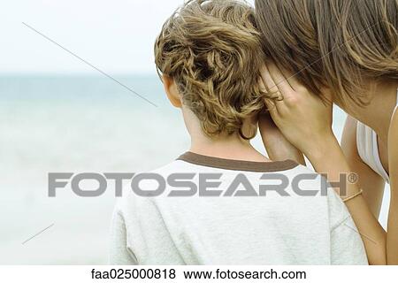 Teenage girl whispering in boy's ear, cropped rear view View Large Photo Image Stock Photo - Teenage girl whispering in boy's ear, cropped rear view. Fotosearch