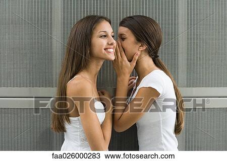 Teenage girl whispering in twin sister's ear, side view View Large Photo Image Stock Image - Teenage girl whispering in twin sister's ear, side view. Fotosearch