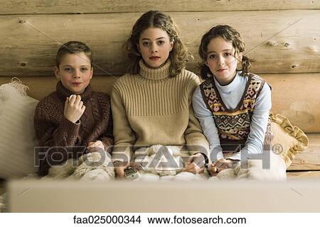 Three young siblings watching TV and eating marshmallows View Large Photo Image Picture - Three young siblings watching TV and eating marshmallows. Fotosearch