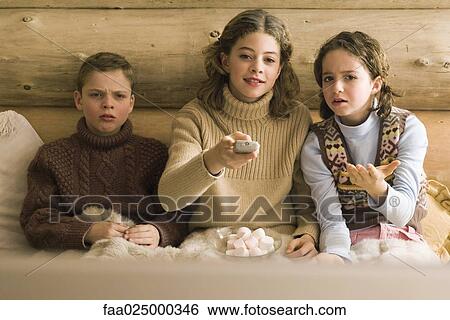 Three young siblings watching TV, teen girl changing channel while brother and sister complain View Large Photo Image Stock Photograph - Three young siblings watching TV, teen girl changing channel while brother and sister complain. Fotosearch