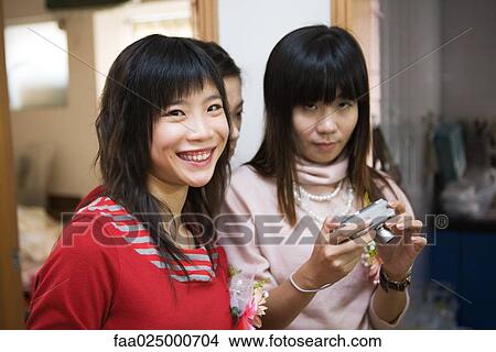 Three young women wearing corsages, one holding digital camera View Large Photo Image Picture - Three young women wearing corsages, one holding digital camera. Fotosearch