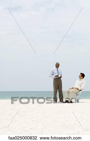 Two business associates chatting on beach, one holding coffee cup View Large Photo Image Stock Image - Two business associates chatting on beach, one holding coffee cup. Fotosearch