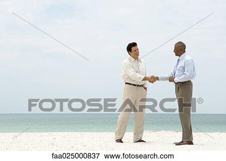 Two businessmen shaking hands on the beach View Large Photo Image Stock Photo - Two businessmen shaking hands on the beach. Fotosearch
