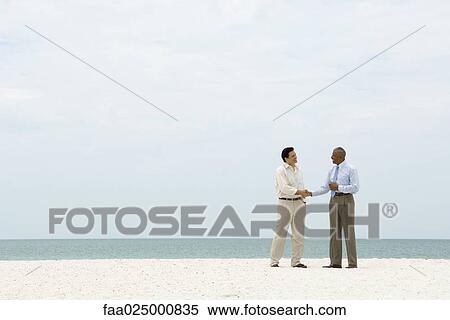 Two businessmen shaking hands on the beach View Large Photo Image Stock Photography - Two businessmen shaking hands on the beach. Fotosearch
