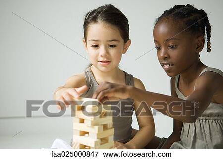 Stock Photo - Two girls building tower with blocks together. Fotosearch