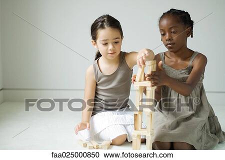 Two girls crouching, building tower with blocks together View Large Photo Image Stock Image - Two girls crouching, building tower with blocks together. Fotosearch