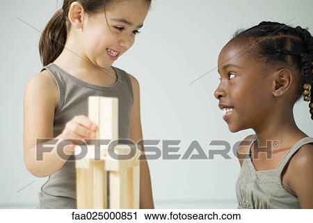 Stock Image - Two girls playing with blocks, smiling at each other. Fotosearch
