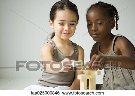 Two girls playing with blocks together, one smiling at camera View Large Photo Image Stock Photograph - Two girls playing with blocks together, one smiling at camera. Fotosearch