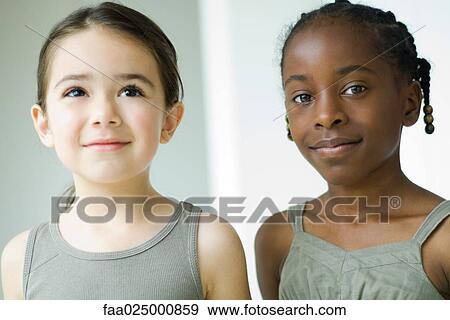 Two girls side by side, one smiling at camera View Large Photo Image Stock Photo - Two girls side by side, one smiling at camera. Fotosearch