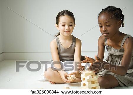 Picture - Two girls sitting on floor stacking blocks. Fotosearch