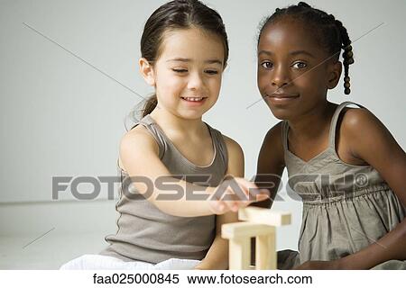 Two girls sitting, playing with blocks, one smiling at camera View Large Photo Image Stock Photography - Two girls sitting, playing with blocks, one smiling at camera. Fotosearch