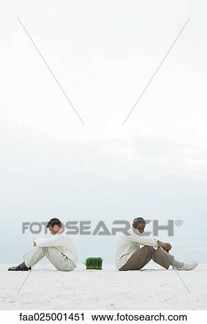 Two men sitting back to back at the beach, wheat grass between them, side view View Large Photo Image Stock Image - Two men sitting back to back at the beach, wheat grass between them, side view. Fotosearch