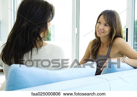 Two women sitting on couch together, smiling View Large Photo Image Stock Photograph - Two women sitting on couch together, smiling. Fotosearch