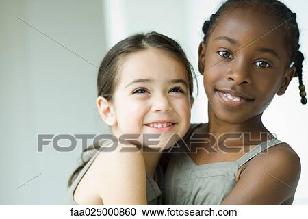 Two young female friends embracing, one smiling at camera View Large Photo Image Stock Image - Two young female friends embracing, one smiling at camera. Fotosearch