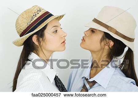 Two young female friends wearing hats and ties, looking at each other View Large Photo Image Stock Photo - Two young female friends wearing hats and ties, looking at each other. Fotosearch