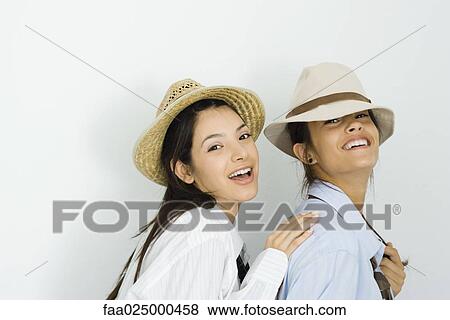 Two young female friends wearing hats and ties, smiling at camera, one placing hand on the other's shoulder View Large Photo Image Stock Photo - Two young female friends wearing hats and ties, smiling at camera, one placing hand on the other's shoulder. Fotosearch