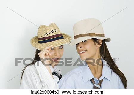 Two young female friends wearing hats and ties, both smiling at camera View Large Photo Image Stock Photo - Two young female friends wearing hats and ties, both smiling at camera. Fotosearch