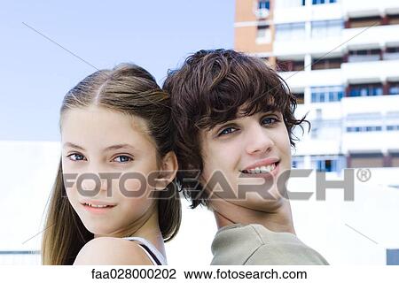 Two young friends back to back, smiling at camera, side view View Large Photo Image Stock Image - Two young friends back to back, smiling at camera, side view. Fotosearch
