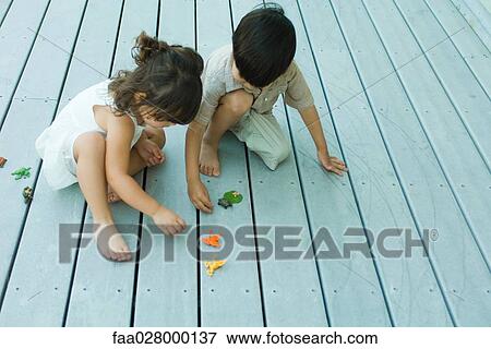 Two young friends crouching together, playing with toys, high angle view View Large Photo Image Stock Photo - Two young friends crouching together, playing with toys, high angle view. Fotosearch