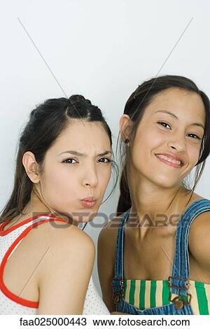 Two young friends looking at camera, one making faces, the other smiling View Large Photo Image Stock Image - Two young friends looking at camera, one making faces, the other smiling. Fotosearch