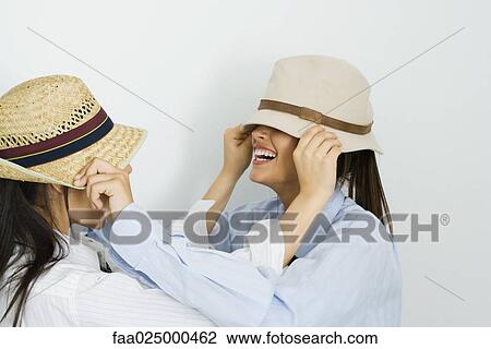 Two young friends pulling hats over each other's faces View Large Photo Image Stock Image - Two young friends pulling hats over each other's faces. Fotosearch