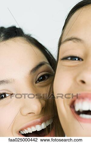 Stock Image - Two young friends smiling at camera, cropped view, close-up. Fotosearch