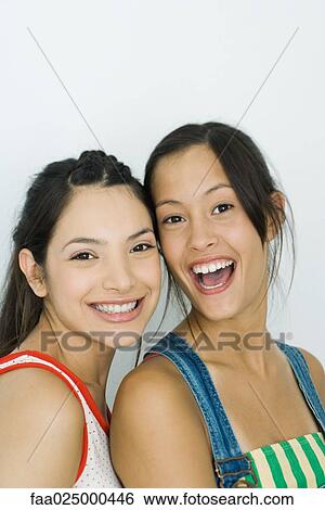 Stock Photograph - Two young friends smiling at camera, portrait. Fotosearch