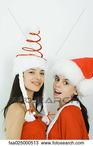 Two young friends wearing Santa hats, smiling at camera View Large Photo Image Stock Image - Two young friends wearing Santa hats, smiling at camera. Fotosearch