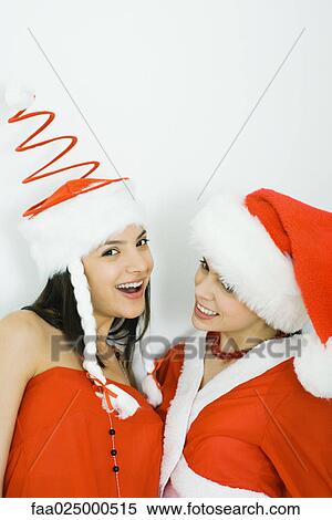 Stock Photography - Two young friends wearing Santa hats, one looking at camera. Fotosearch