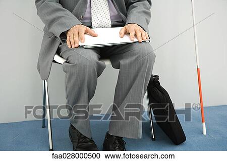 Visually impaired man sitting in chair, holding documents on lap, cropped view, chest down View Large Photo Image Stock Image - Visually impaired man sitting in chair, holding documents on lap, cropped view, chest down. Fotosearch