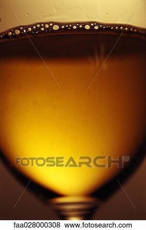 Stock Photo - White wine in glass with bubbles, extreme close-up. Fotosearch