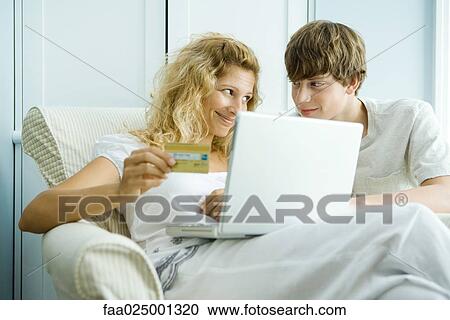 Woman and teen son using laptop, making on-line purchase with credit card View Large Photo Image Stock Image - Woman and teen son using laptop, making on-line purchase with credit card. Fotosearch