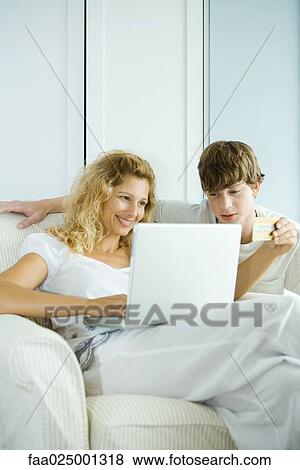Woman and teen son using laptop, making on-line purchase with credit card View Large Photo Image Stock Photo - Woman and teen son using laptop, making on-line purchase with credit card. Fotosearch