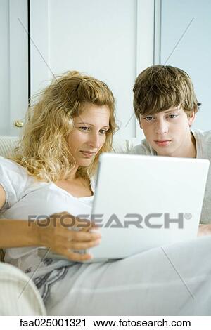 Stock Image - Woman and teen son using laptop. Fotosearch